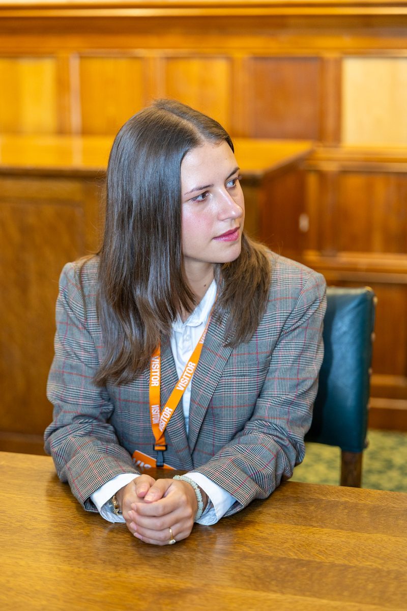 A scholar listening during a meeting in a wood-paneled room